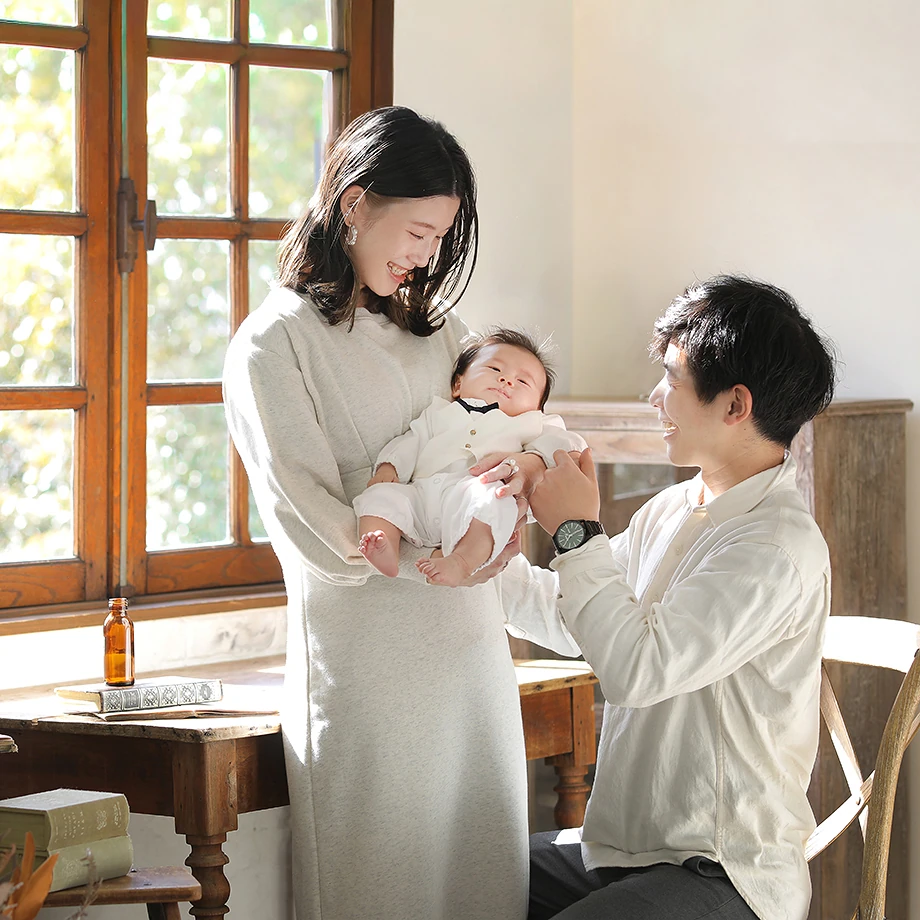 窓の近くで赤ちゃんを見守るお母さんとお父さん