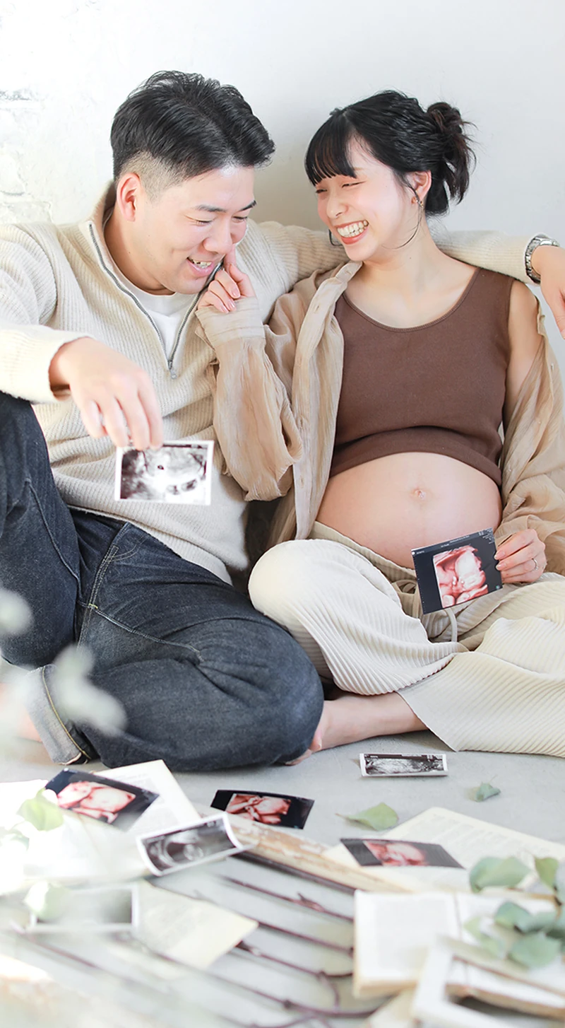 お腹の赤ちゃんのエコー写真を見ている笑顔の夫婦