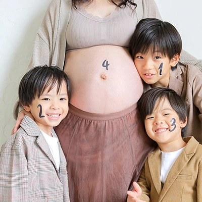 「4」という数字がかかれたマタニティのお母さんのお腹を囲む3人のきょうだい達